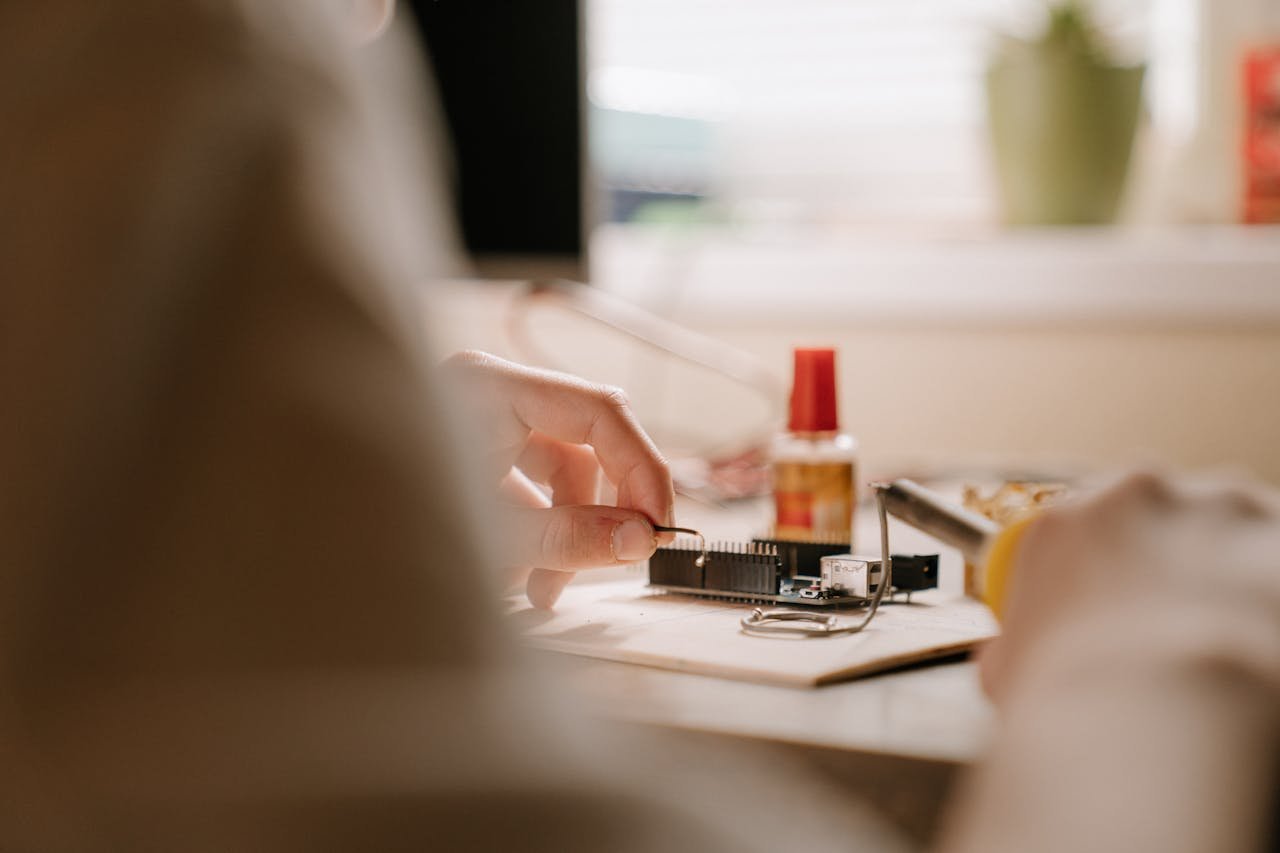 who-we-are A detailed view of soldering a printed circuit board with tools indoors, ideal for technology enthusiasts.